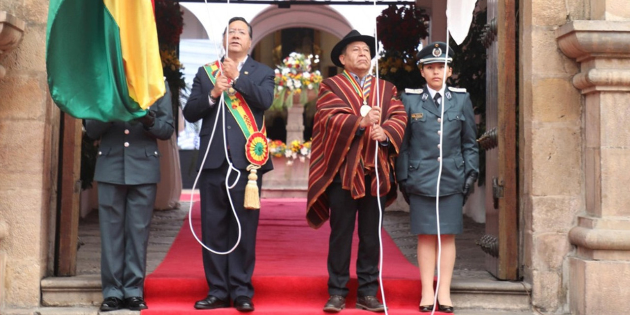 El presidente Luis Arce y el vicepresidente David Choquehuanca en la iza de la bandera nacional.